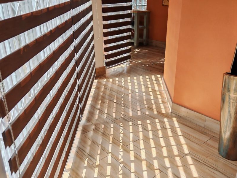 A bright hallway featuring modern zebra blinds, tiled flooring, and a decorative glass block window, creating a clean and well-lit transition space.