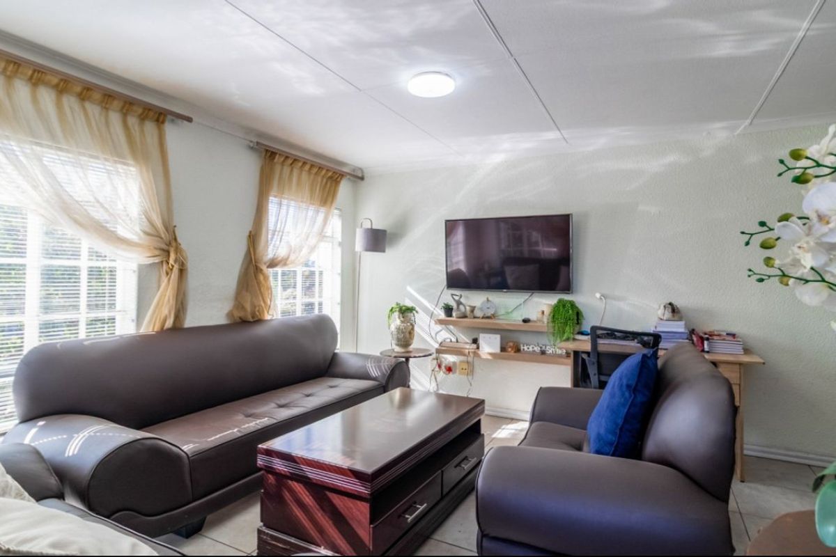 A bright living room featuring tiled flooring and large windows that provide ample natural light, creating a comfortable and functional living space.