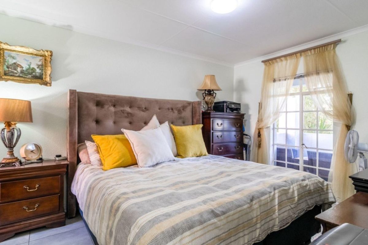 A bedroom featuring tiled flooring, coved ceilings, and direct access to an outdoor area through glass-paned french doors.