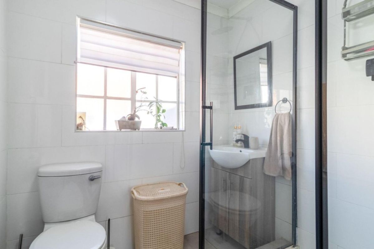 A modern bathroom featuring a glass-enclosed shower, a vanity unit with a basin, and white wall tiling.