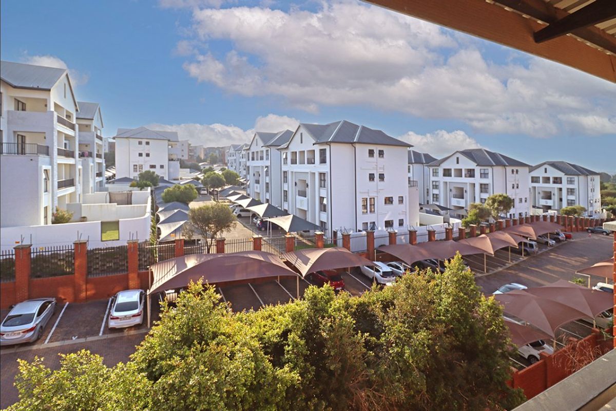 Elevated view of the apartment complex grounds, featuring paved parking areas with shade-cloth carports and well-maintained multi-story residential buildings.