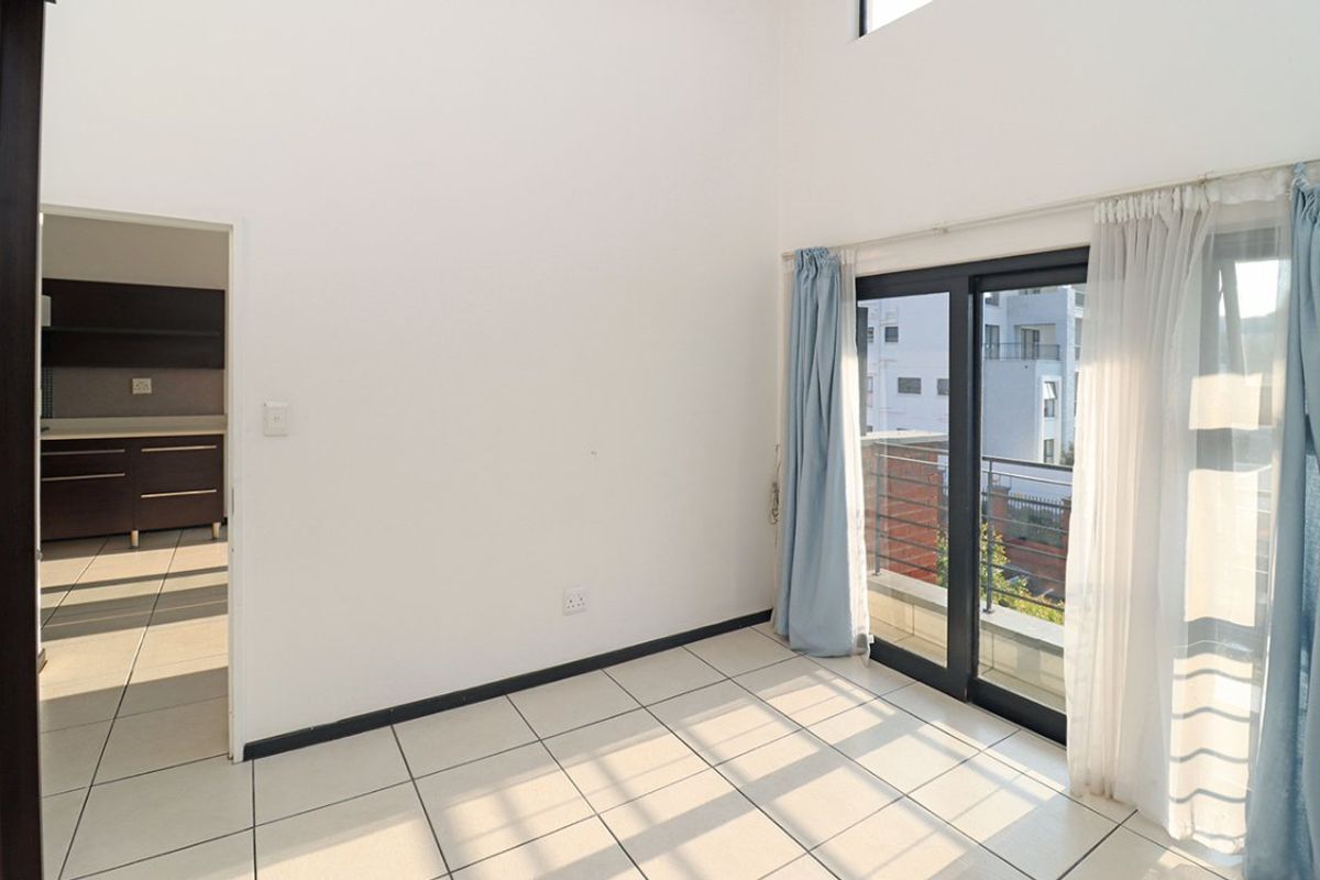 Bright and spacious living area featuring tiled floors, high ceilings, and direct access to a private balcony through sliding glass doors.