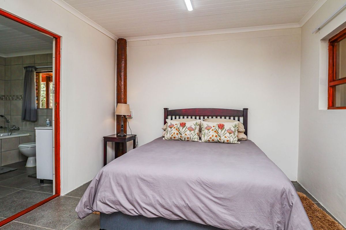 A bedroom featuring tiled flooring, a timber ceiling, and an exposed support post, with direct access to an en-suite bathroom.