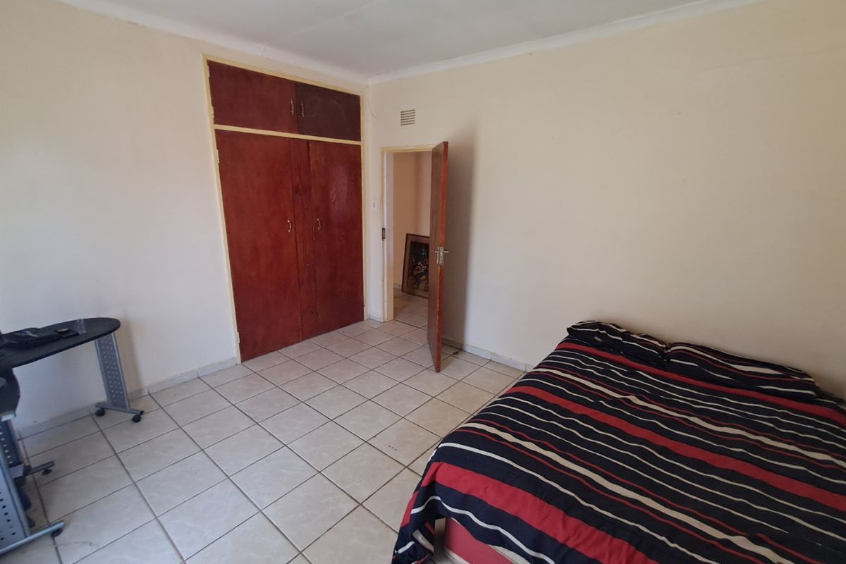 A bedroom featuring tiled flooring and a built-in wardrobe, offering a functional space with potential for cosmetic updates.