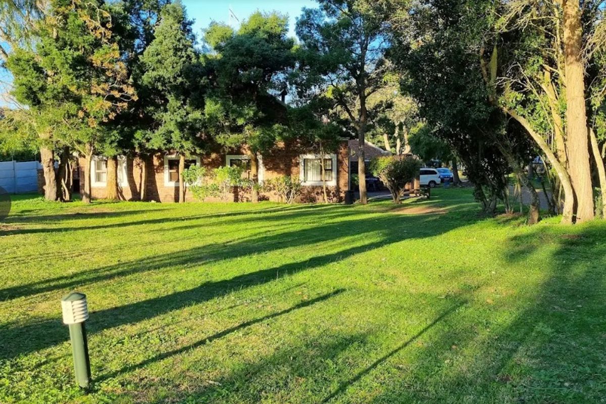 A view of the rear brick facade of the commercial property, featuring a spacious lawn and mature trees.
