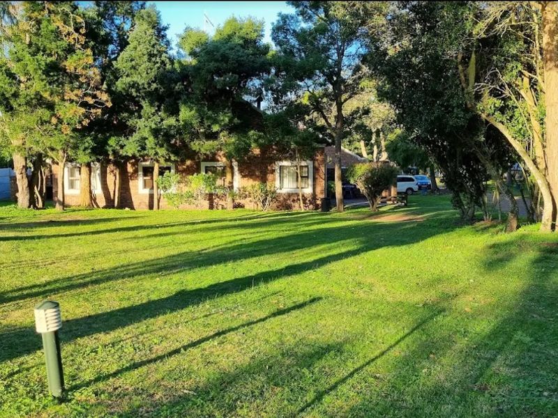 A view of the rear brick facade of the commercial property, featuring a spacious lawn and mature trees.