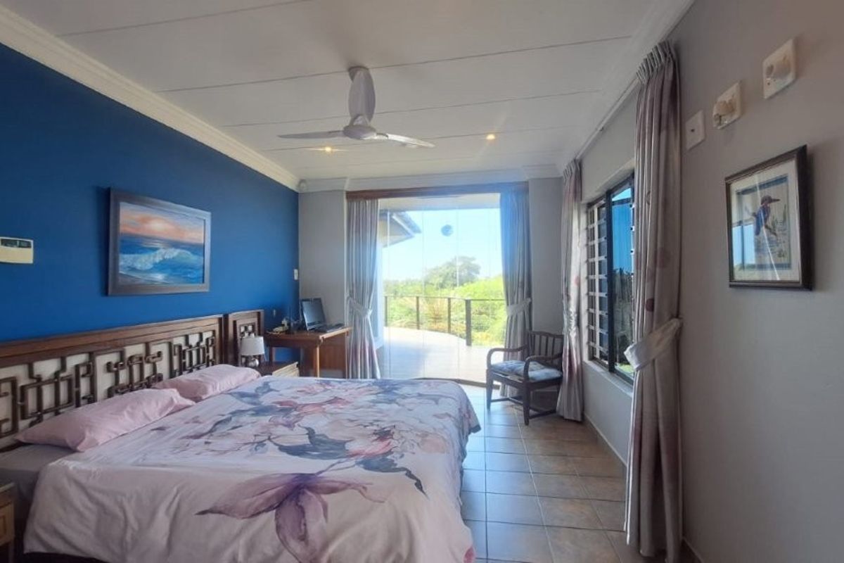 Spacious bedroom featuring tiled flooring, a ceiling fan, and large sliding glass doors that open onto an outdoor deck area.