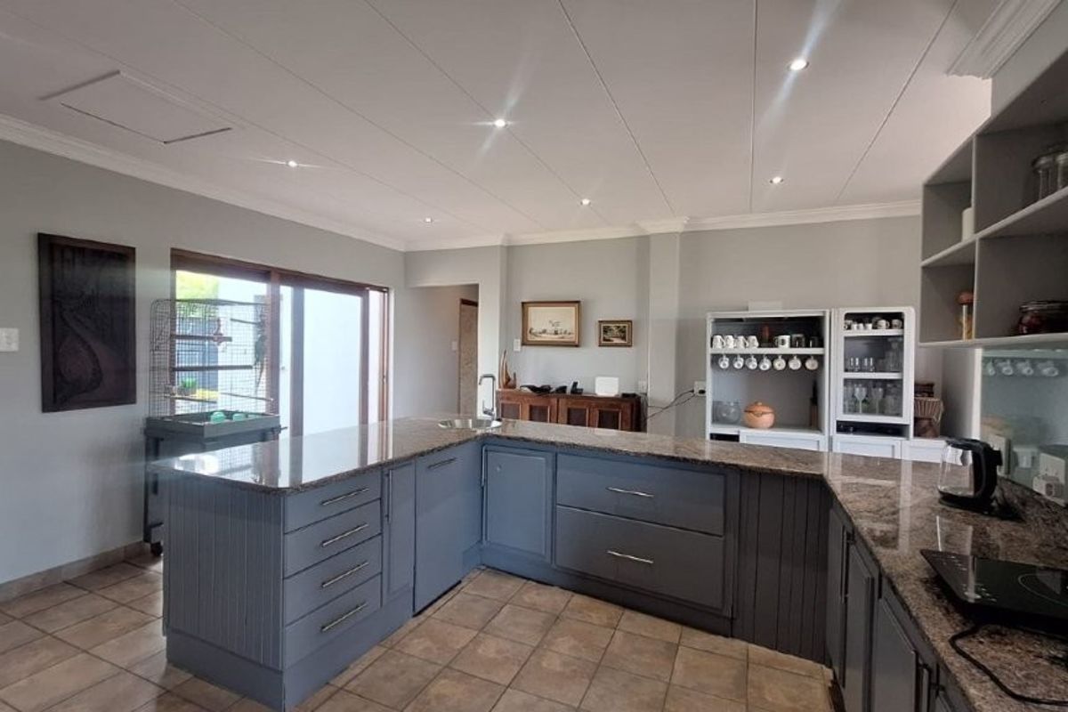 A well-maintained kitchen featuring granite countertops, ample built-in cabinetry, tiled flooring, and recessed lighting, offering a functional and clean workspace.