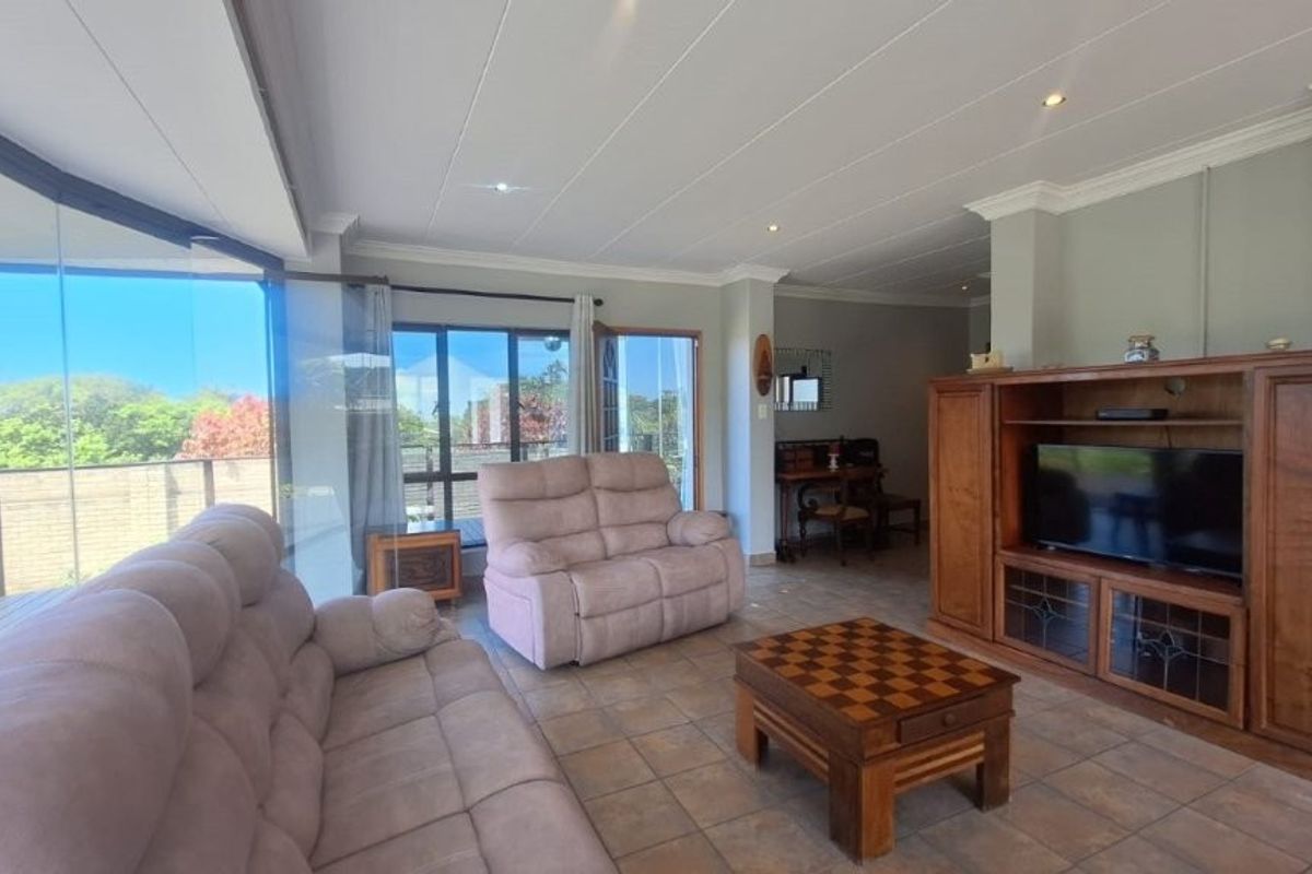 Spacious living room featuring tiled flooring, recessed lighting, and large glass sliding doors that provide ample natural light and access to the outdoor area.