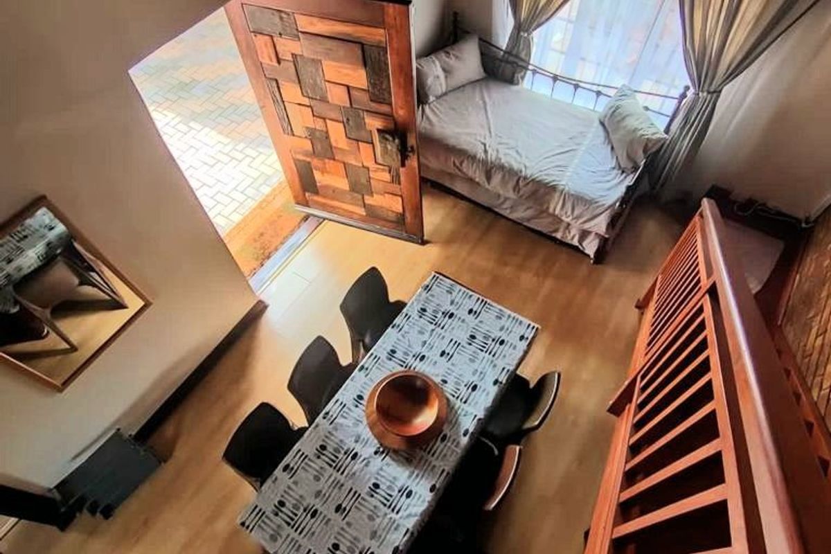 A high-ceiling living area featuring a traditional thatch roof with exposed timber rafters, wooden staircase, and direct access to the exterior.