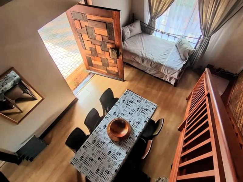 A high-ceiling living area featuring a traditional thatch roof with exposed timber rafters, wooden staircase, and direct access to the exterior.