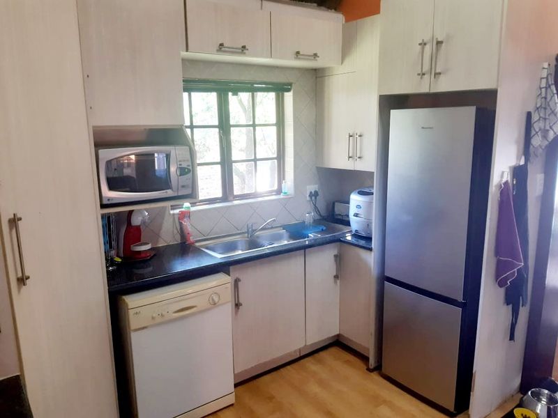 Compact kitchen featuring built-in cabinetry, laminate countertops, a double basin sink, and tiled backsplash, offering a functional layout for daily use.