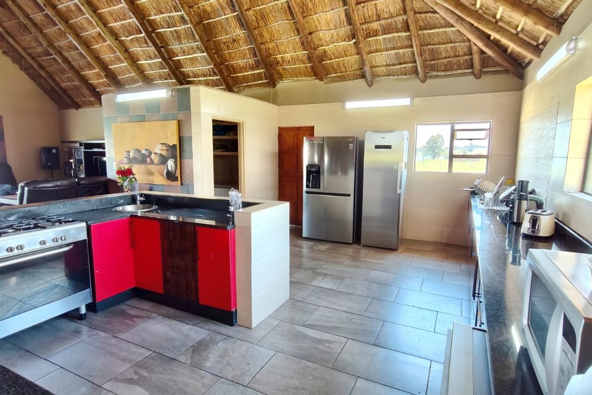 Spacious kitchen featuring a high thatched ceiling, granite countertops, gas stove, and tiled flooring, offering a unique rustic aesthetic with modern functionality.