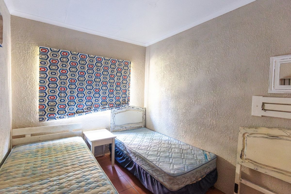 A compact bedroom featuring textured wall finishes, tiled flooring, and a coved ceiling, offering a functional space ready for cosmetic updates.