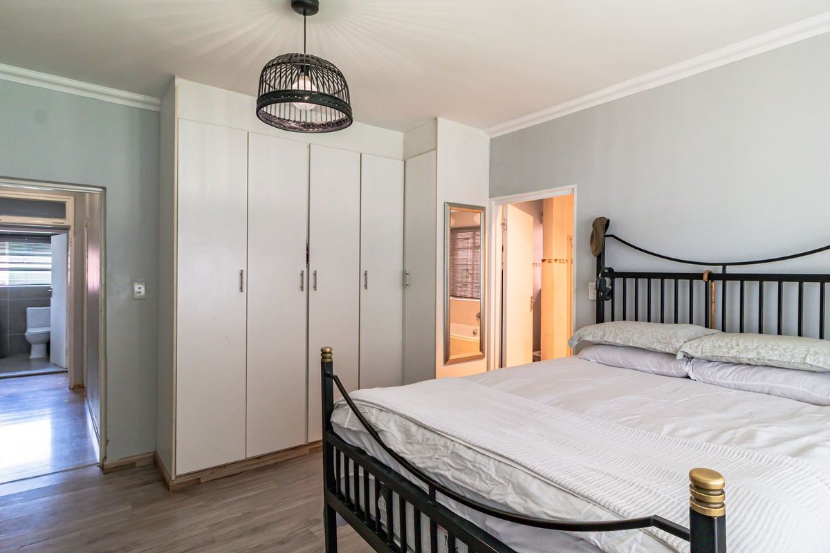 A well-maintained bedroom featuring built-in cupboards, laminate flooring, and direct access to an en-suite bathroom.