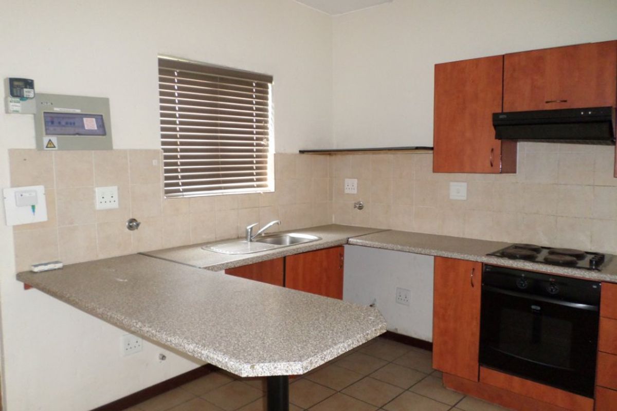 A functional kitchen featuring laminate cabinetry, built-in oven and hob, tiled backsplash, and a breakfast nook counter, currently vacant and ready for updates.