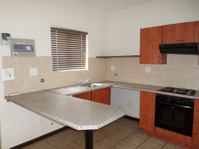 A functional kitchen featuring laminate cabinetry, built-in oven and hob, tiled backsplash, and a breakfast nook counter, currently vacant and ready for updates.