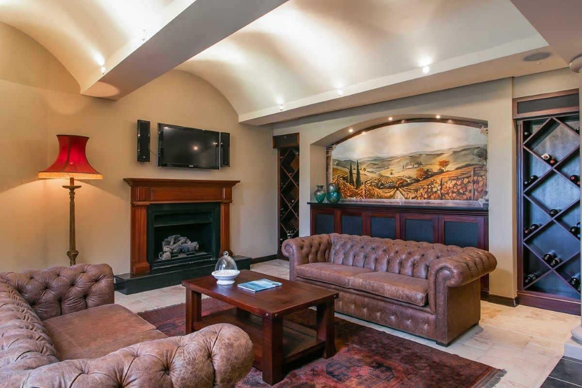 A cozy living room featuring a vaulted ceiling, recessed lighting, a built-in fireplace with a wooden mantel, and integrated wine storage cabinetry.