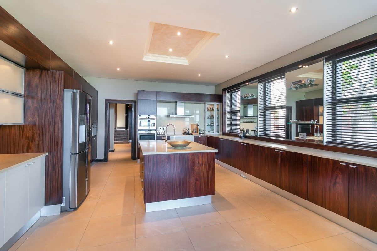 Modern kitchen featuring dark wood cabinetry, a central island with stone countertops, built-in appliances, and recessed lighting throughout.