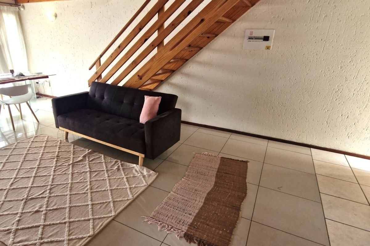 Open plan living area featuring tiled flooring and a wooden staircase leading to the upper level.