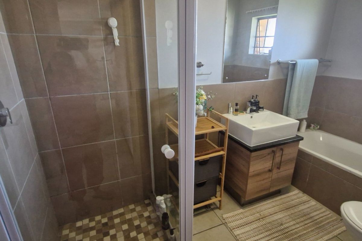 A functional bathroom featuring a shower enclosure, a bathtub, a vessel sink vanity, and neutral wall tiling.