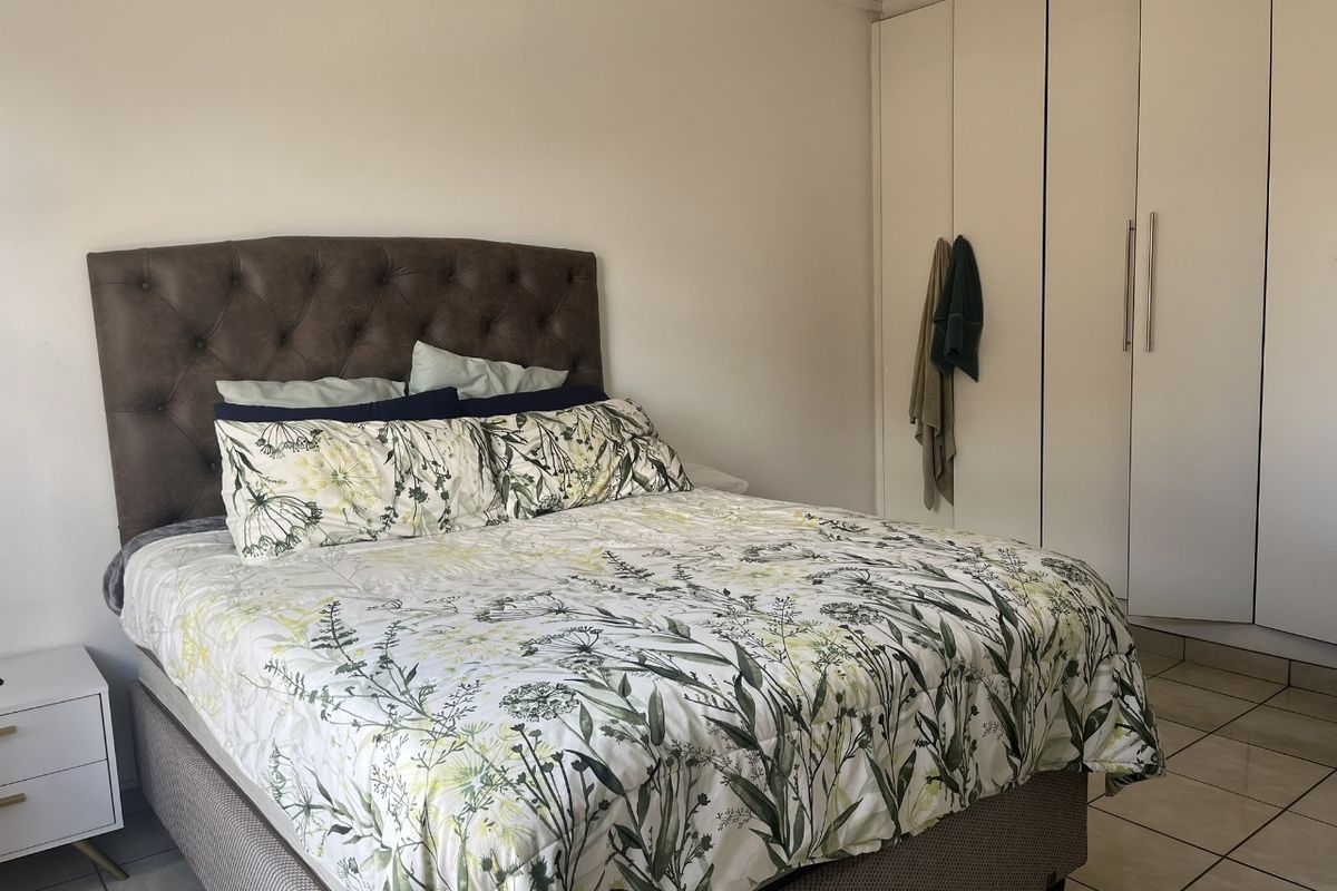 A well-maintained bedroom featuring neutral tiled flooring and ample built-in cupboard storage space.