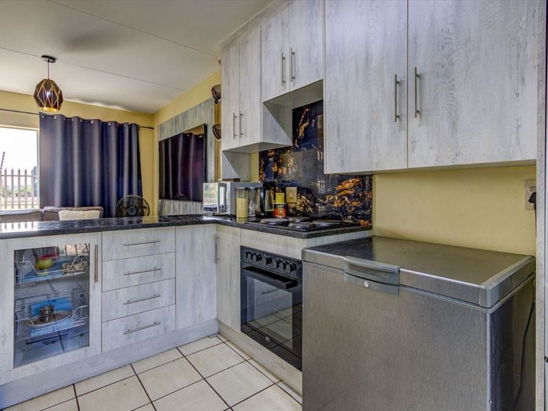 Compact kitchen featuring light wood-grain cabinetry, dark granite countertops, a built-in oven and hob, and a decorative splashback.