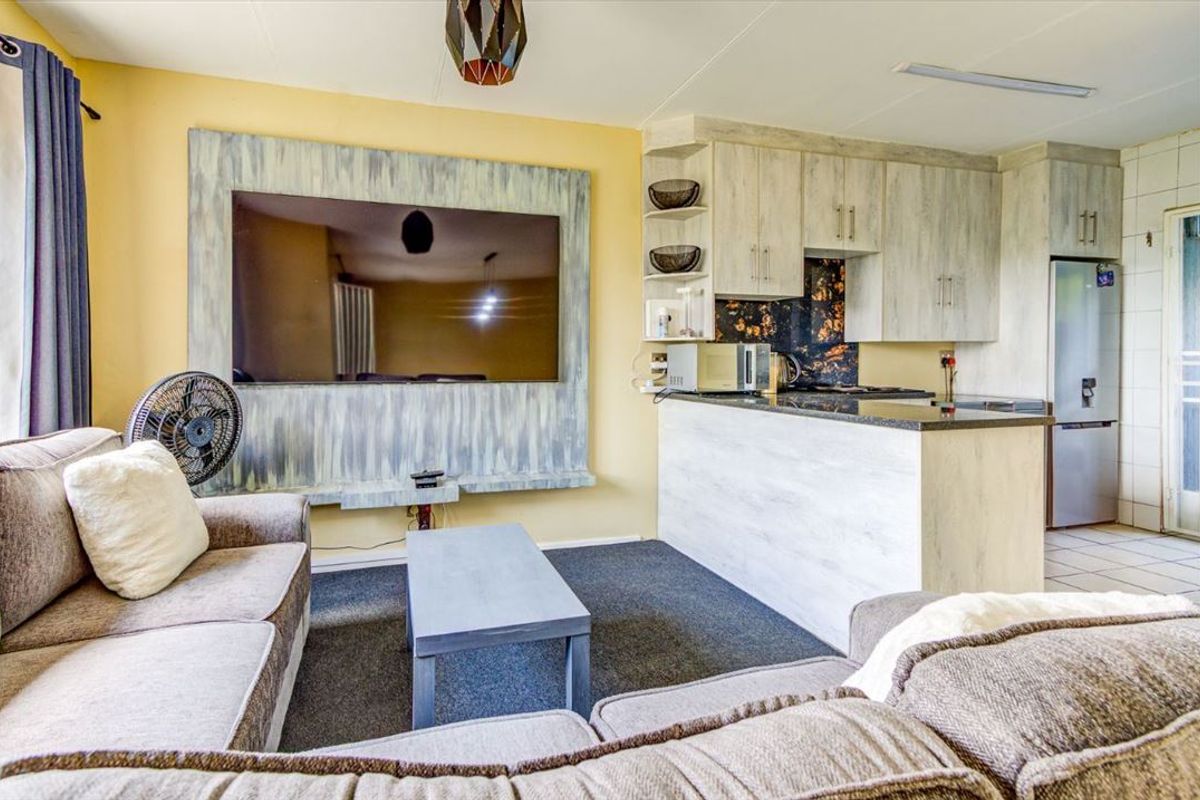 Open-plan living area featuring a compact kitchen with granite countertops and built-in cabinetry, seamlessly connected to a comfortable lounge space.