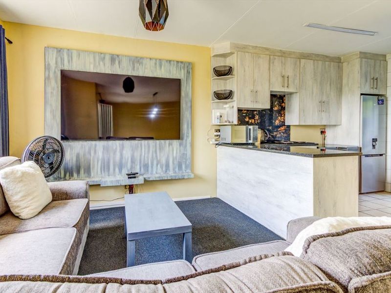 Open-plan living area featuring a compact kitchen with granite countertops and built-in cabinetry, seamlessly connected to a comfortable lounge space.