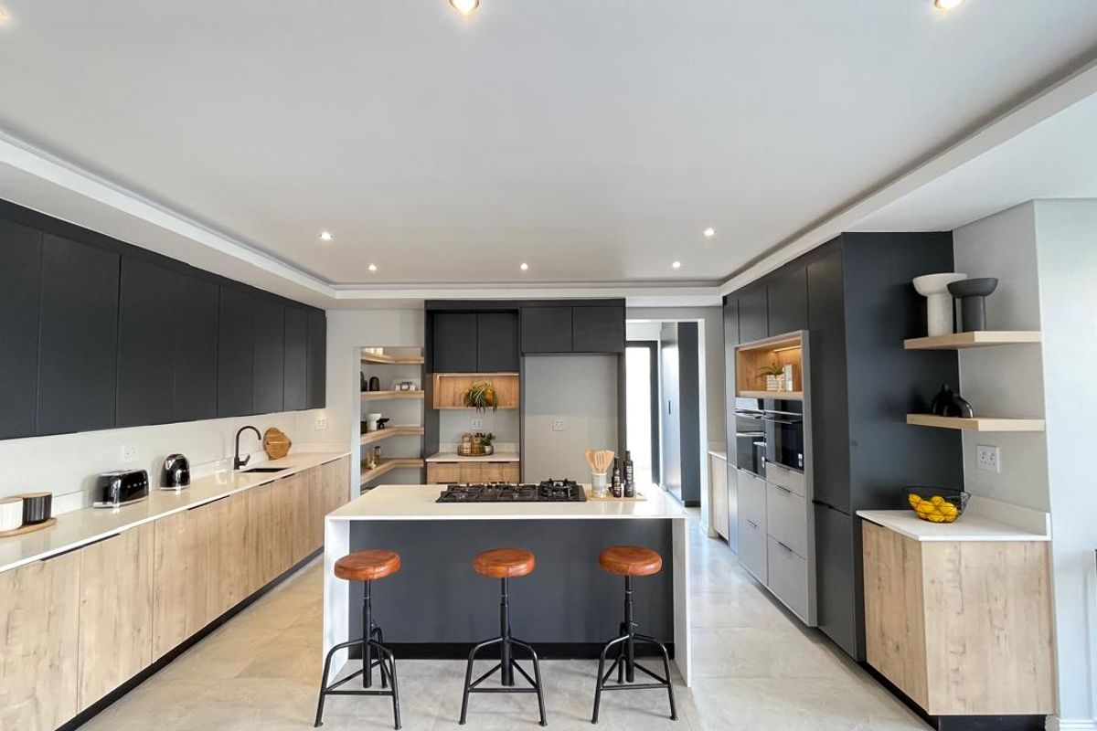 Modern, high-end kitchen featuring a central island, sleek two-tone cabinetry, stone countertops, and integrated appliances with contemporary recessed lighting.