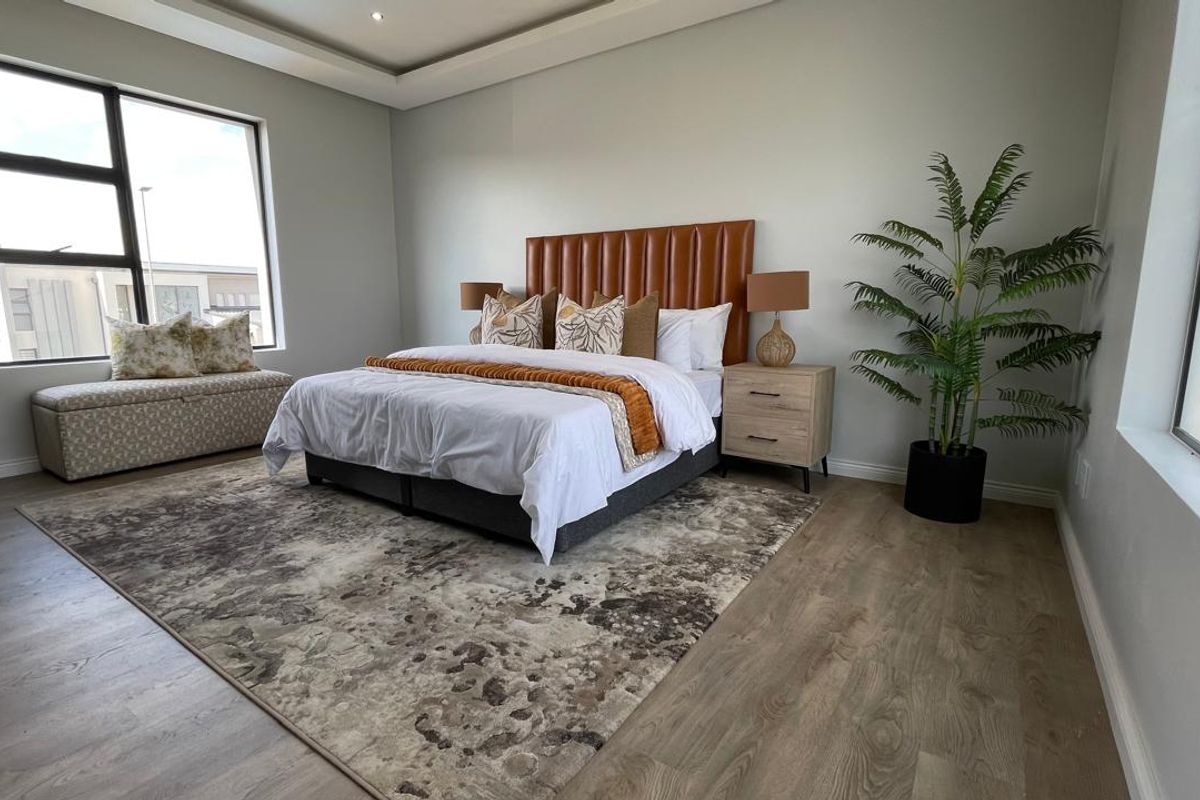 Spacious modern bedroom featuring high-quality laminate flooring, a recessed ceiling design, and large windows that provide ample natural light.