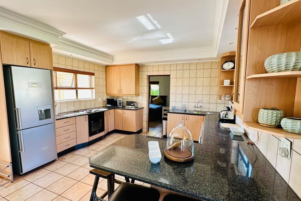 A functional kitchen featuring light wood cabinetry, granite countertops, tiled backsplash, and a breakfast bar, offering a practical layout for daily cooking and dining.