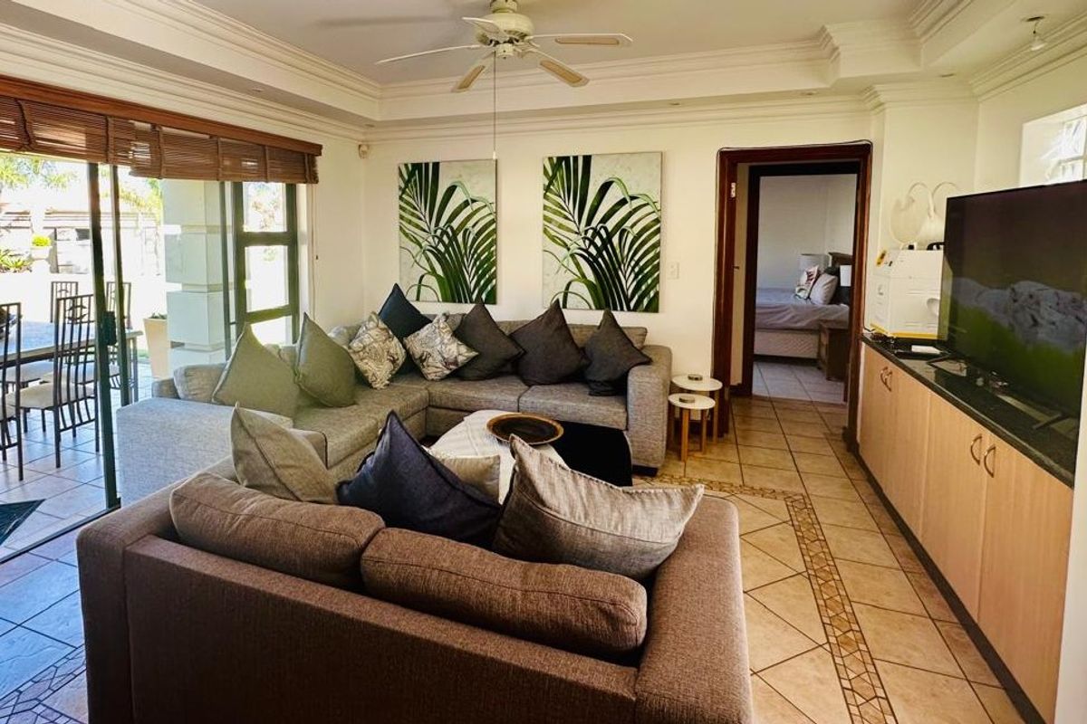 Spacious living room featuring tiled flooring, a ceiling fan, and large sliding glass doors that provide seamless access to the outdoor patio area.