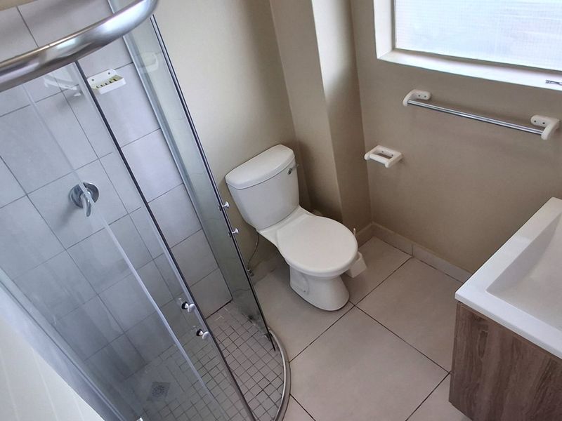 A clean, modern bathroom featuring a glass shower enclosure, a contemporary vanity with a basin, and a standard toilet.