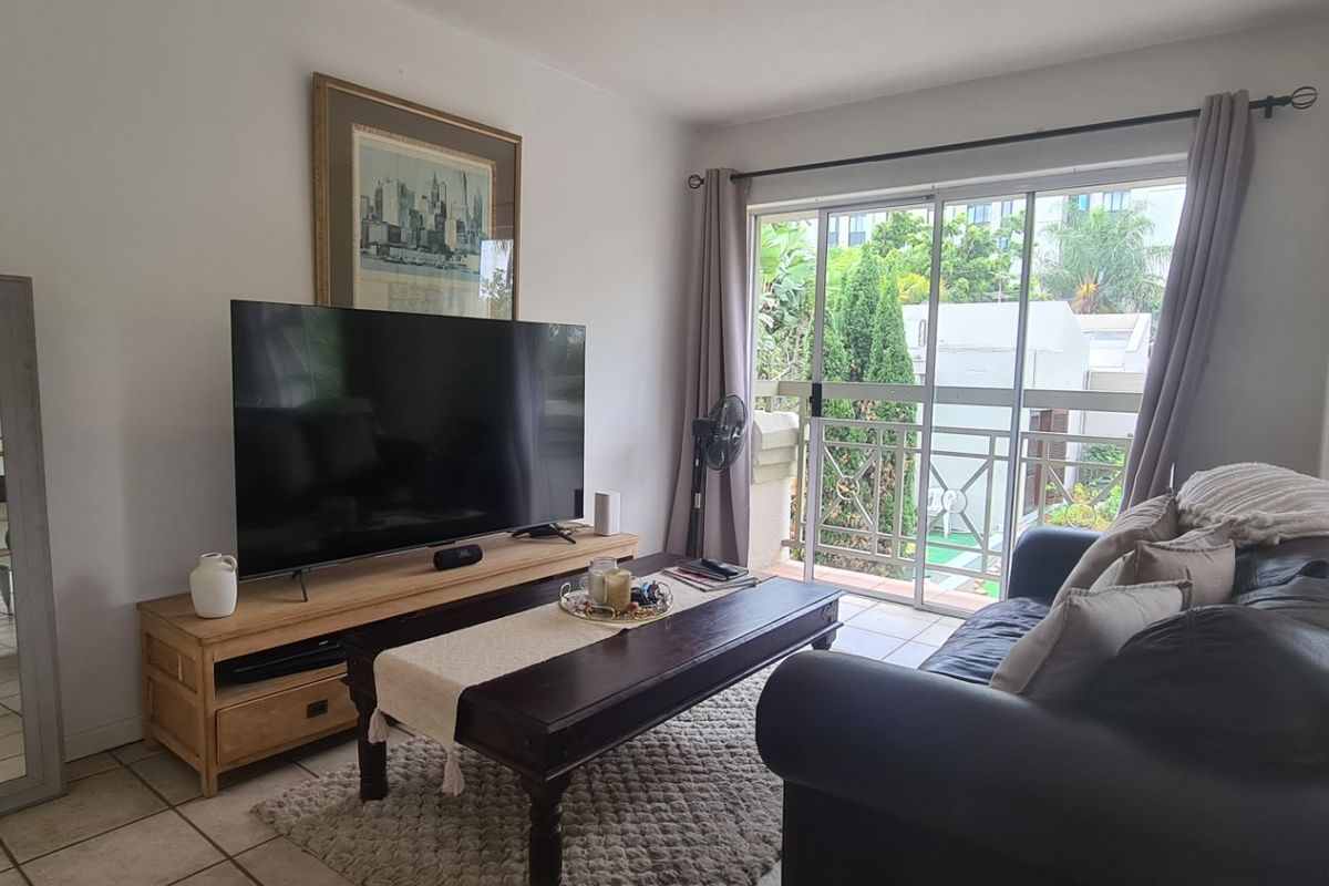 A comfortable living room featuring tiled flooring and a large sliding glass door that provides access to a private balcony.