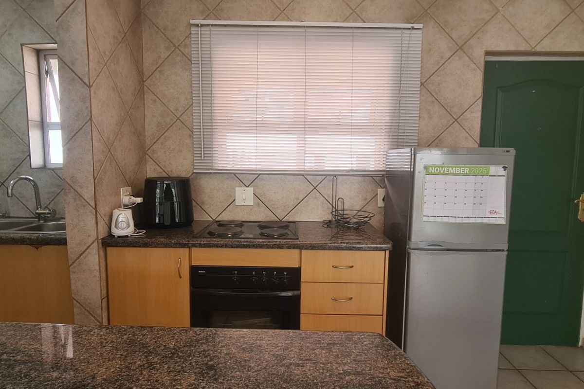 Functional kitchen featuring granite countertops, built-in oven, electric hob, and tiled backsplash with ample storage cabinetry.