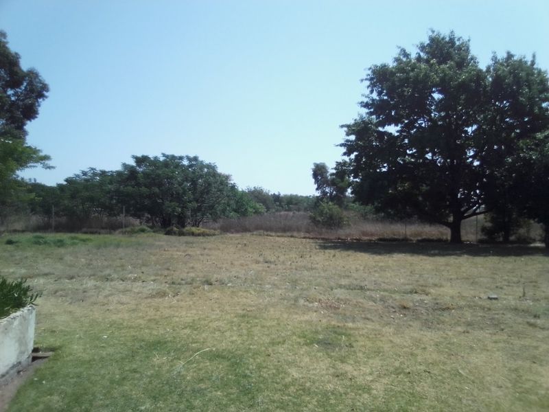 A view of the expansive garden area featuring mature trees and perimeter fencing on the farm property.
