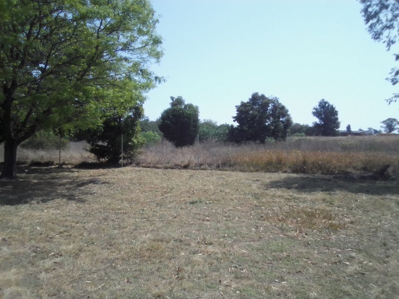 An expansive open garden area on the farm property featuring mature trees and perimeter wire fencing.