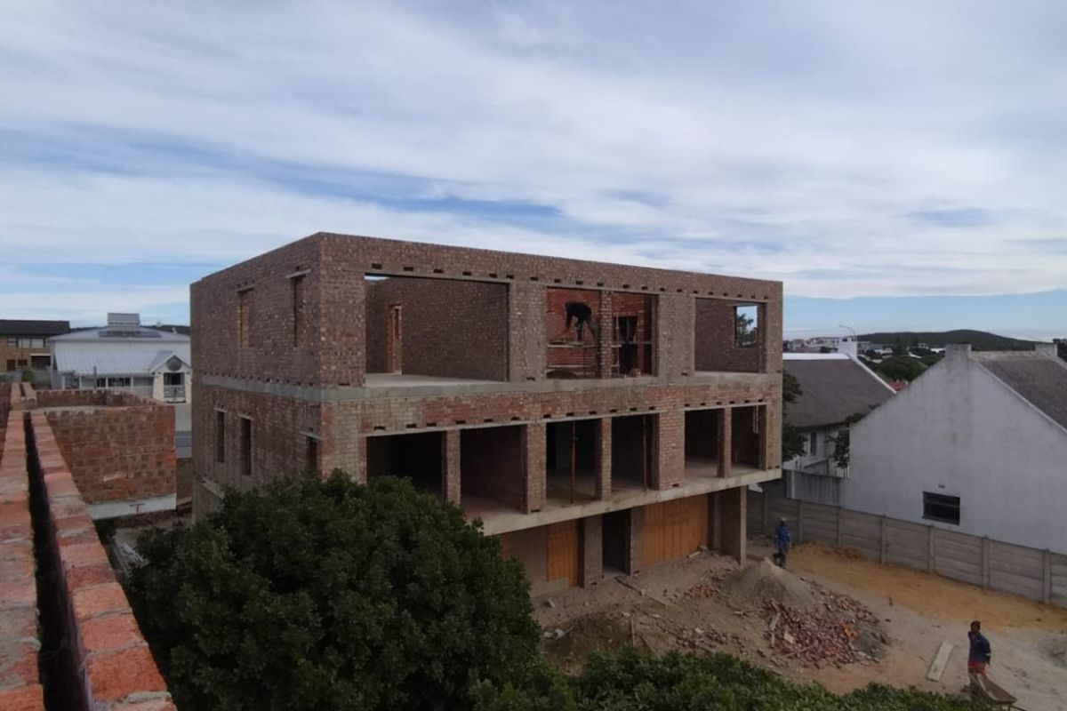 An elevated view of a multi-story commercial building currently under construction, featuring exposed brickwork and structural concrete framing.