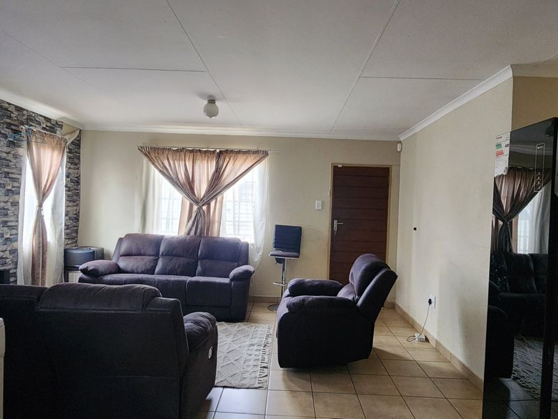A living room featuring tiled flooring, a stone-effect feature wall, and an integrated air conditioning unit.