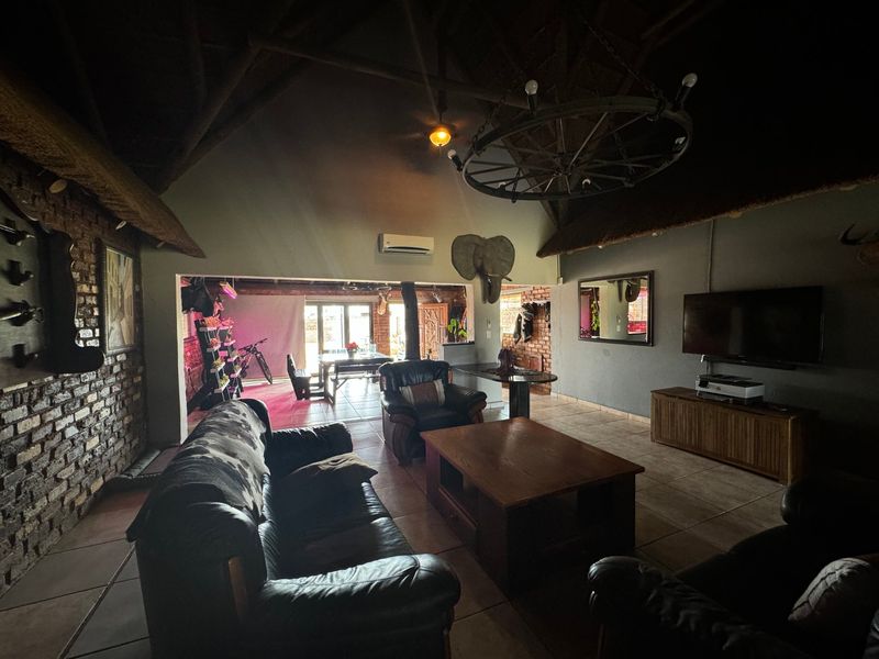 Spacious open-plan living area featuring exposed brick walls, high thatch ceilings with timber trusses, and tiled flooring, creating a rustic commercial atmosphere.