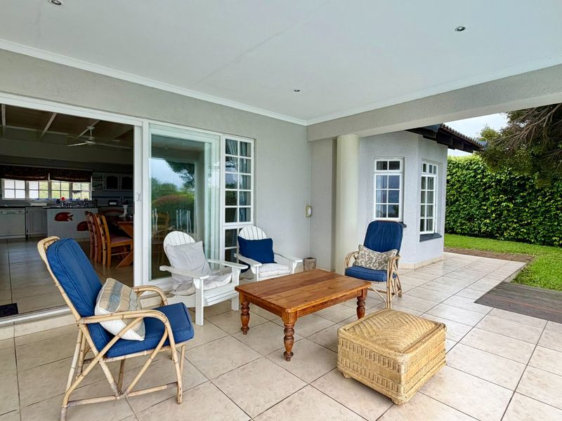 A spacious covered patio featuring tiled flooring and recessed lighting, providing seamless indoor-outdoor flow through large sliding glass doors.