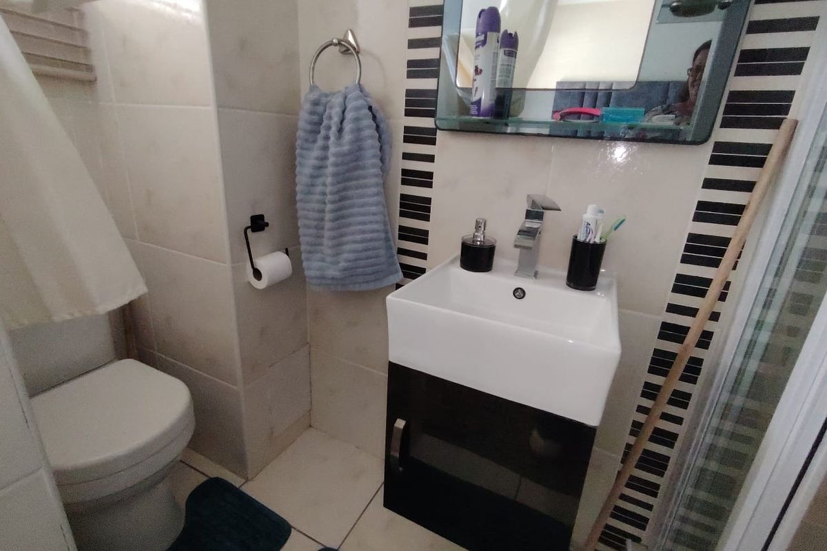 A compact bathroom featuring a modern wall-mounted vanity with basin, tiled walls with decorative accents, and a standard toilet.