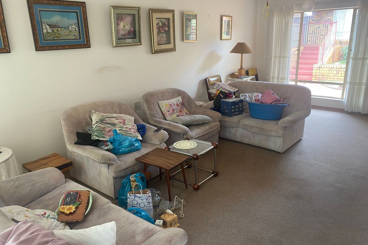 A spacious living room featuring neutral carpeting, a ceiling fan, and large sliding glass doors providing access to the exterior.