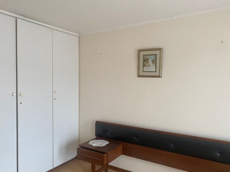A bedroom featuring a built-in wardrobe with white doors and a neutral wall finish.