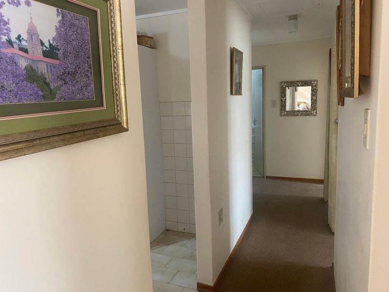 A functional hallway featuring carpeted flooring and a small tiled alcove area, providing access to adjacent rooms within the townhouse.
