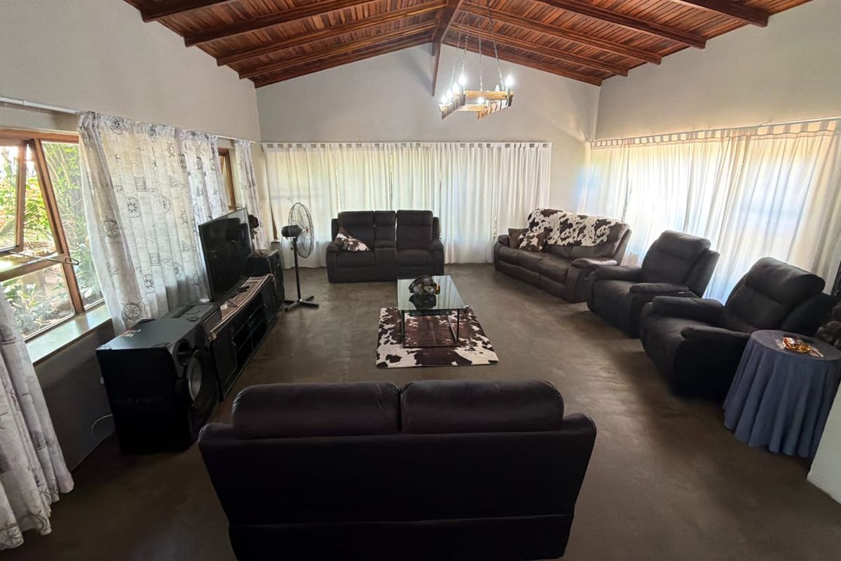 Spacious living room featuring a high vaulted timber rafter ceiling, polished concrete floors, and abundant natural light through large windows.