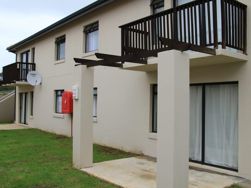 Rear view of the apartment building featuring ground floor patios, upper level balconies with timber pergolas, and sliding door access.