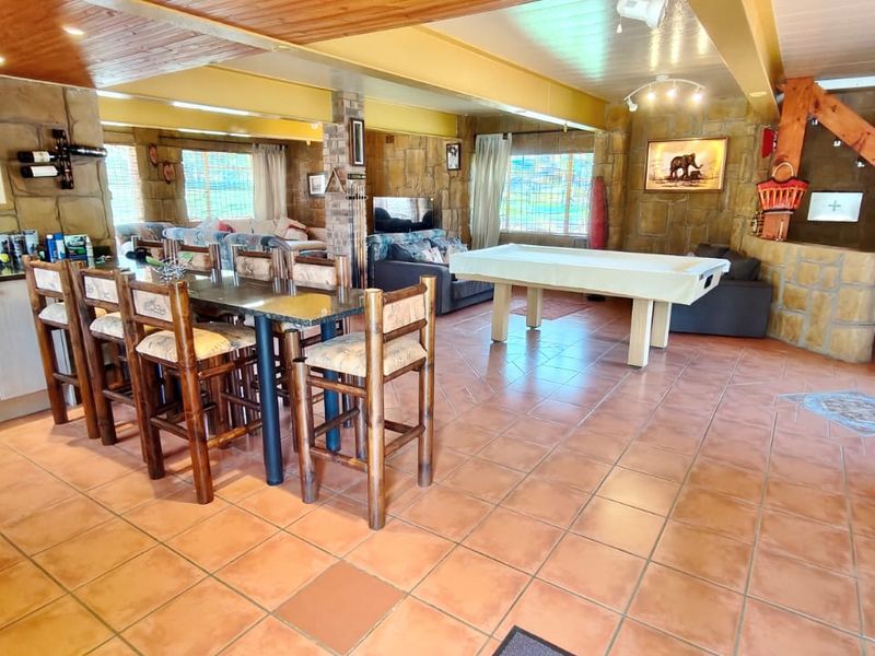 Spacious open-plan living and dining area featuring rustic stone wall cladding, timber ceilings, and terracotta floor tiles with integrated kitchen cabinetry.