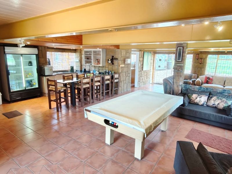 Spacious open-plan entertainment area featuring stone-clad walls, tiled flooring, and a built-in bar counter, ideal for social gatherings and leisure activities.